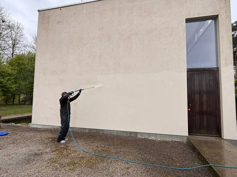 Medewerker van MOS Reinigingsservice die een crepigevel reinigt met een telescooplans.